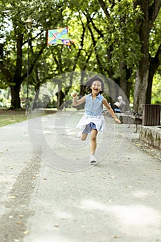 Little Asian girl running happily with a kite in the park