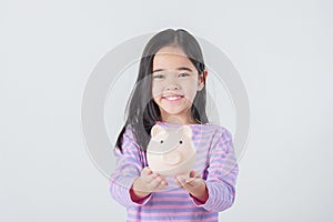 Little Asian girl saving money in a piggy bank