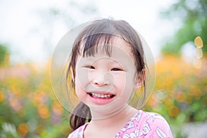 Little asian girl smiling at camera in flower garden