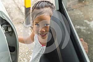 Little asian girl trying to open the door of a car and smile