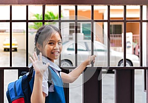 Little asian girl in uniform say good bye before leaving to school in the morning with blue back pack