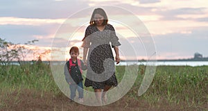 Little asian girl walking in the nature with her mom, Mother holding hands of her daughter. Children walk to explore nature for