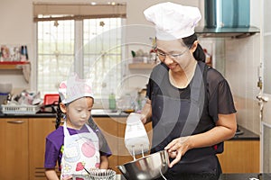 Little asian girls and mother making sponge cake
