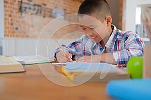 little asian kid boy schoolboy writing drawing on notebook. child children doing homework.