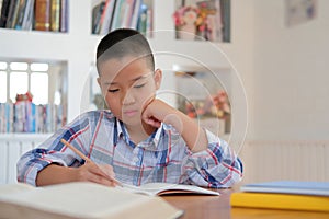 little asian kid boy schoolboy writing drawing on notebook. child children doing homework.