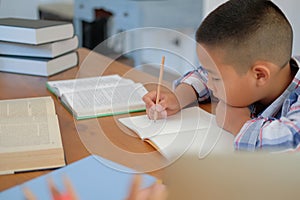 little asian kid boy schoolboy writing drawing on notebook. child children doing homework.