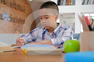 little asian kid boy schoolboy writing drawing on notebook. child children doing homework.