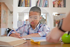 little asian kid boy schoolboy writing drawing on notebook. child children doing homework.