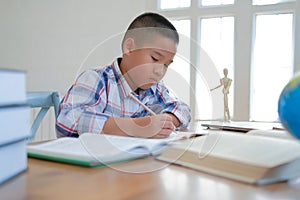 little asian kid boy schoolboy writing drawing on notebook. child children doing homework.