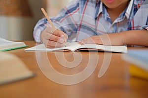 little asian kid boy schoolboy writing drawing on notebook. child children doing homework.