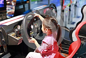 Little Asian kid girl playing game arcade Racing car