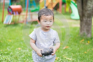 Little Asian kid holding a radio remote control (controlling han