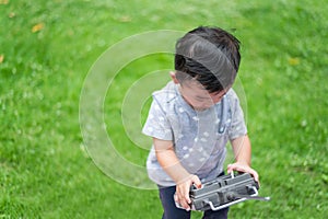 Little Asian kid holding a radio remote control (controlling han