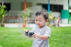 Little Asian kid holding a radio remote control (controlling han