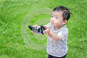 Little Asian kid holding a radio remote control (controlling han