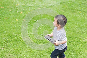 Little Asian kid holding a radio remote control (controlling han