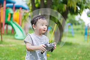 Little Asian kid holding a radio remote control controlling han
