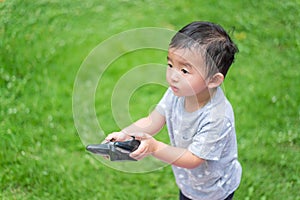 Little Asian kid holding a radio remote control controlling han