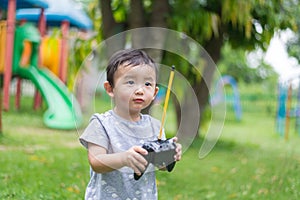 Little Asian kid holding a radio remote control controlling han