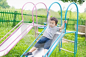 Little Asian kid playing slide at the playground