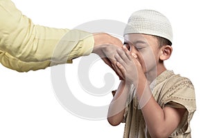 Little asian muslim kid in white cap kissing parents hand