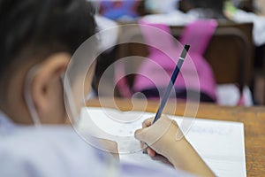 Little asian school girl writing notebook homework with pencil photo