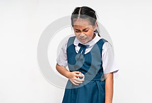 Little Asian student girl is stomach ache, unidentified school uniform, isolated portrait of Asian child girl with stomach pain on