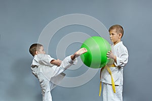 Little athlete kicks a green ball against a gray background