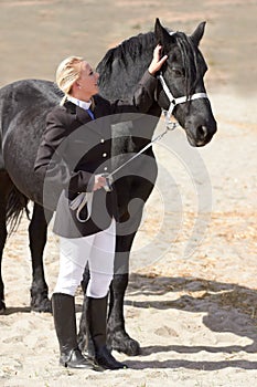 A little attention goes a long way. High angle shot of a young female rider stroking her horse affectionately.