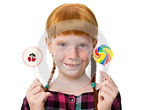 Little attractive redheaded girl with freckles holding colorful candy