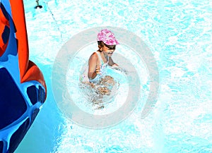 Little Ñaucasian girl in a cap and swimsuit plays in the pool on vacation. Children`s entertainment at sea. Vacation with