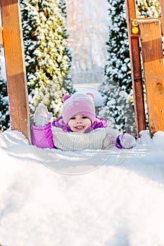 Little babe girl playing on the winter playground.