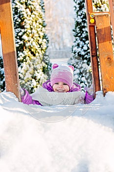 Little babe girl playing on the winter playground.