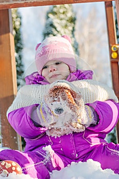 Little babe girl playing on the winter playground.