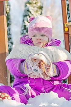 Little babe girl playing on the winter playground.