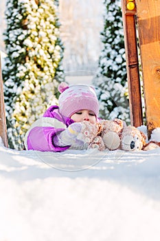 Little babe girl playing on the winter playground.