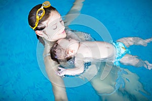 Little baby with blue eyes learning to swim