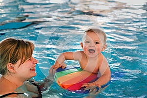 Little baby with blue eyes learning to swim