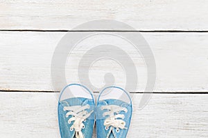 Little baby blue sneakers on a white wooden background