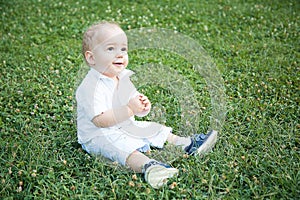 Little baby boy blond dressed in a white shirt posing for the photo