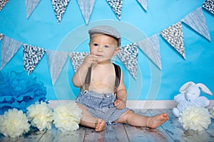 Little baby boy, celebrating his first birthday with smash cake party, studio isolated shot on blue