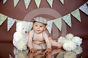 Little baby boy, celebrating his first birthday with smash cake party, studio isolated shot on brown