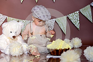 Little baby boy, celebrating his first birthday with smash cake party, studio isolated shot on brown