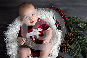 Little baby boy with christmas clothes in basket, looking curiou photo