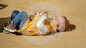 Little baby boy crying and screaming on the street ground. Upset children, negative emotions, kids problems
