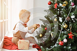 Little baby boy decorating a Christmas tree toys. Holidays, gift, and new year concept