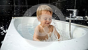 Little baby boy enjoying his bath time and playing with water, foam and sponge. The image highlights the significance of bath time