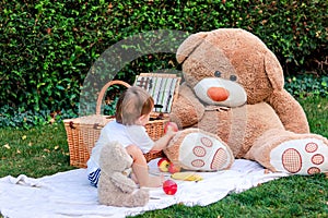 Little baby boy having picnic with teddy toys in garden