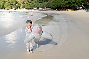 A Little baby boy with inflatable toy float playing in the water on summer vacation in a tropical resort. Kid with toy shark on a