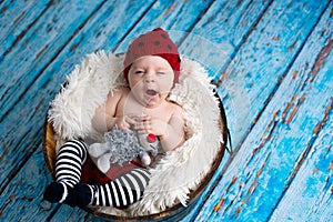 Little baby boy with knitted hat in a basket, happily smiling